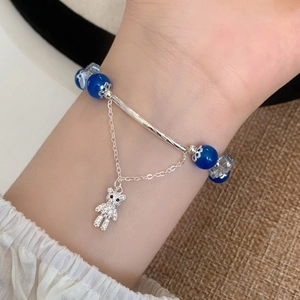 Bracelet en perles de verre bleues avec barre argentée et breloque ourson sertie