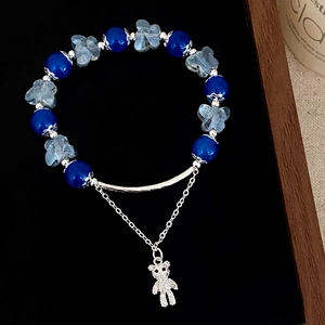 Gros plan d'un bracelet en perles de verre bleu avec pendentif ours sur présentoir en velours