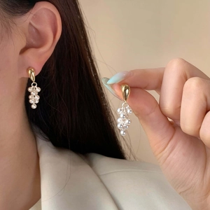 Elegant grape cluster pearl earrings with gold metal accents shown on model and held
