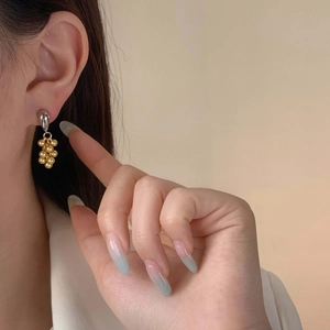 Luxurious gold and silver grape-shaped tassel earrings in matte finish on a model