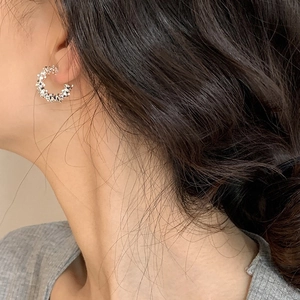 Silver C-shaped textured earrings with lava-style metallic finish on female model