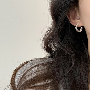 Detailed view of silver C-shaped hoop earrings with textured bead pattern on model