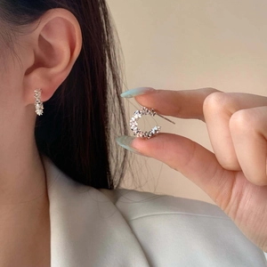 Detail of silver C-shaped earrings with a crushed silver texture on model's ear