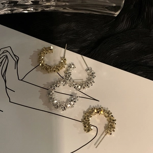 C-shaped textured earrings in gold and silver finish on a minimalist display card