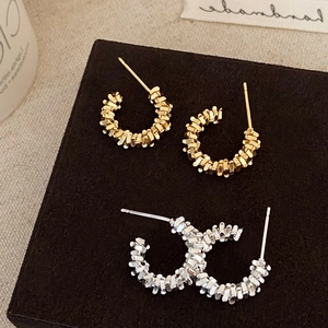 Detailed view of textured silver and gold C-shaped earrings on a premium display