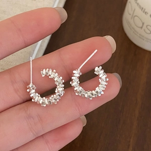 Macro shot of silver C-shaped earrings with unique geometric crushed silver texture