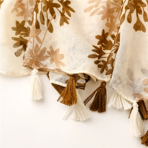 Close-up of floral pattern and fringe tassels on a beige cotton-linen feel scarf