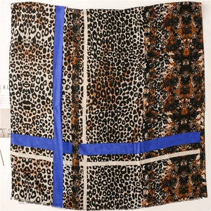 Detail of leopard and snake print scarf with vibrant blue geometric color blocks