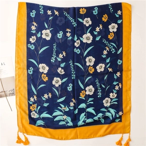 Detailansicht des Schals mit Blumenmuster, blauer Basis und orangefarbenen Quasten