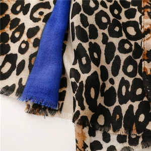 Detailed macro view of leopard print cotton scarf with blue color block and frayed edges