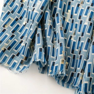 Detail of blue geometric cotton-linen scarf with gold foil dots and fringe edges