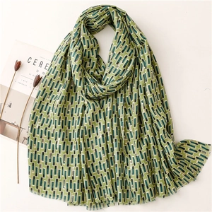 Artistic green geometric pattern linen scarf with gold accents and frayed edges on white