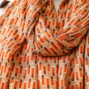 Detail of soft linen-feel scarf with geometric patterns and golden foil stamping accents