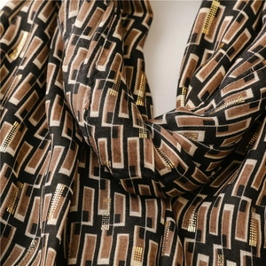 Macro view of geometric scarf with metallic gold lines and soft cotton-linen texture