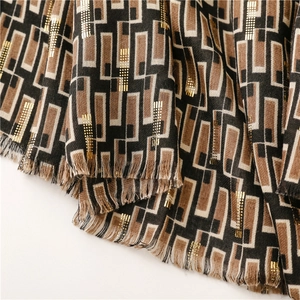 Detailed close-up of woven geometric scarf with gold metallic thread and frayed fringe edges