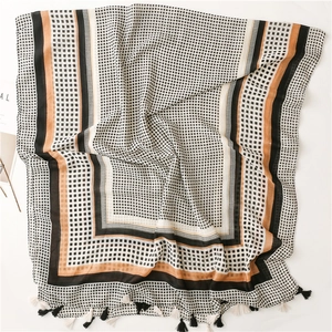 Detail of soft linen-touch scarf featuring black white grid pattern and tassel fringe
