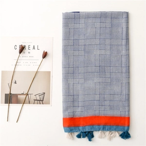 Detail eines blau-weiß karierten Schals mit orangefarbenen Akzenten und Fransenquasten