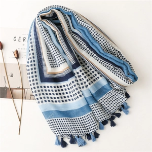 Detail of blue and white geometric scarf with delicate fringe tassels on white background