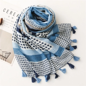Detail of blue and white scarf featuring geometric patterns and soft tassels