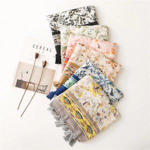 Flat lay of multiple floral cotton scarves with soft tassels in various colors and patterns