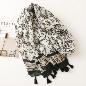 Detailed macro view of ethnic floral cotton scarf with delicate black tassels and soft texture
