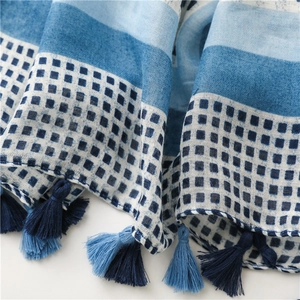 Close-up of cotton-linen scarf texture with blue stripes and handmade fringes