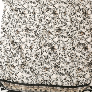Detail of floral printed scarf featuring black vine patterns and ethnic tassel borders