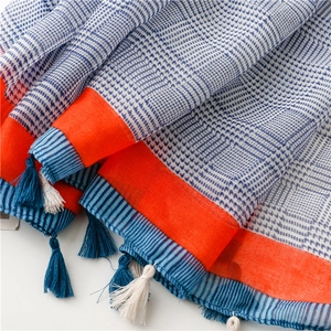 Detail eines blau karierten Schals mit orangefarbenem Rand und Fransenverzierung