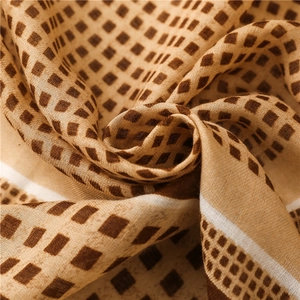 Close-up of khaki cotton scarf featuring brown geometric squares and breathable knit texture