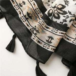 Close-up of ethnic floral print scarf fabric featuring delicate handmade black tassels