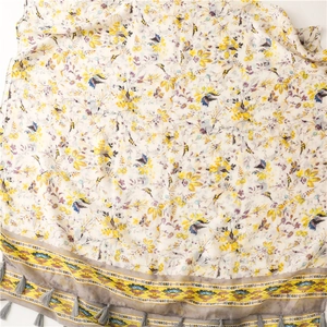 Detail of floral cotton linen scarf featuring yellow blossoms and grey fringe tassels