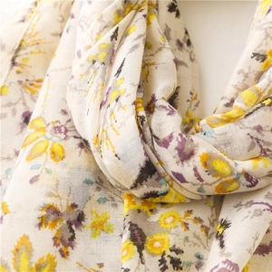 Close-up of soft cotton scarf featuring yellow and purple floral patterns with tassels