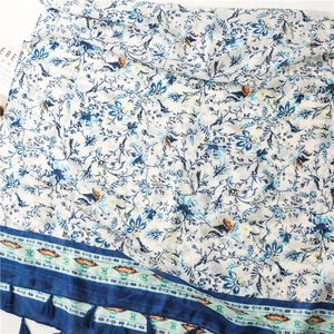 Close-up of floral scarf featuring blue tassels and intricate bird pattern details