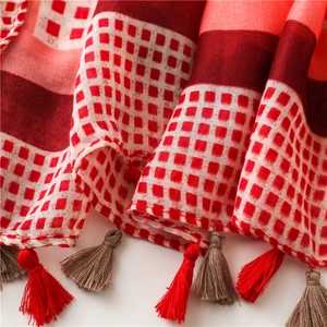 Detail of red and white checkered cotton scarf with decorative fringe and soft texture
