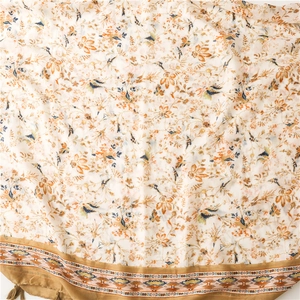 Detail of floral and bird print scarf with ethnic woven borders and soft tassel charms