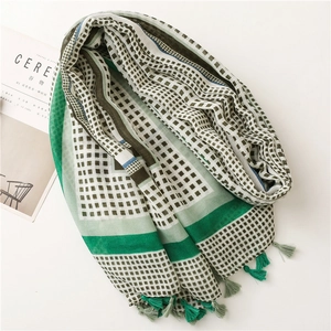 Detail of green checkerboard scarf with fine handmade tassels and soft linen texture