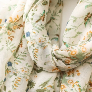 Close-up of soft floral cotton scarf texture with green and orange botanical prints