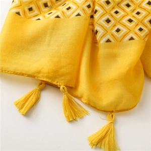 Détail macro du foulard jaune à motifs géométriques avec franges et texture tissée