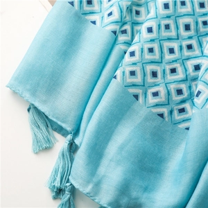 Gros plan détaillé d'une écharpe en coton et lin bleu clair avec pompons et motifs carrés