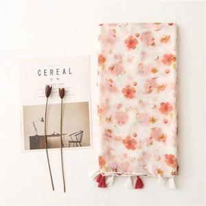 Floral cotton linen scarf in pink with tassels, styled with a magazine on white background