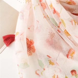 Detailed view of lightweight floral scarf fabric with pink blossoms and red tassels