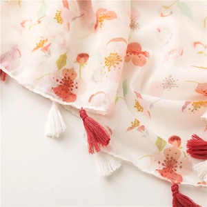 Detail of floral Bali yarn scarf with pink cherry blossoms and delicate red fringe tassels