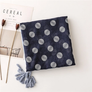 Detail of navy blue polka dot scarf with light blue tassels on a minimalist background