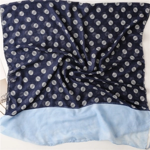 Detailed view of dark blue polka dot scarf with light blue hem and soft fringe edges