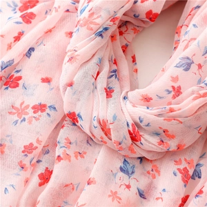 Detail of soft pink cotton scarf featuring red and blue floral patterns and light texture
