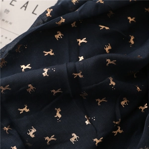 Detailed close-up of navy scarf with gold foil unicorn prints and fine textile texture