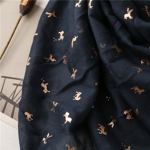 Detail of navy cotton scarf featuring shimmering gold horse patterns and twill texture