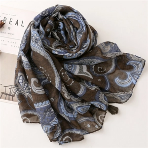 Close-up of deep brown paisley print scarf with fringe details on a white surface