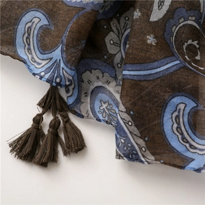 Detail of dark brown paisley scarf featuring intricate blue patterns and woven fringe