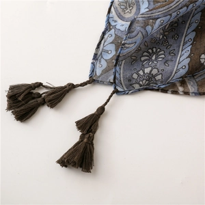 Detail of bohemian paisley scarf with intricate blue patterns and brown tassels